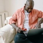 Man sits in a chair and interacts with his laptop