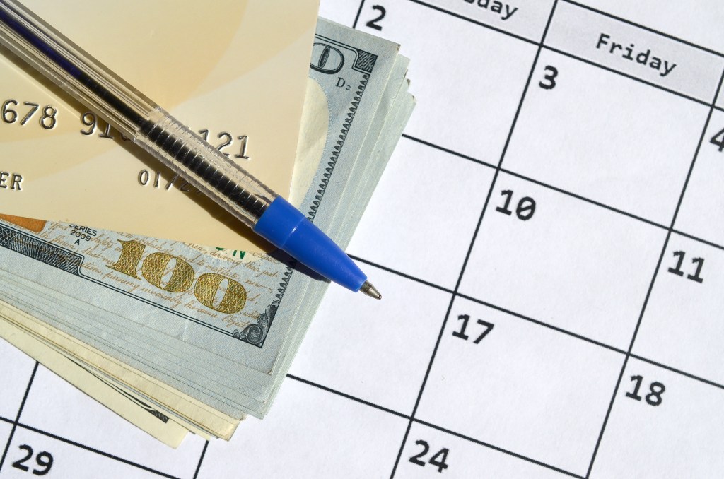 Close-up of a calendar, credit card, and cash with a pen, symbolizing payment scheduling and financial planning for Buy Now, Pay Later services.